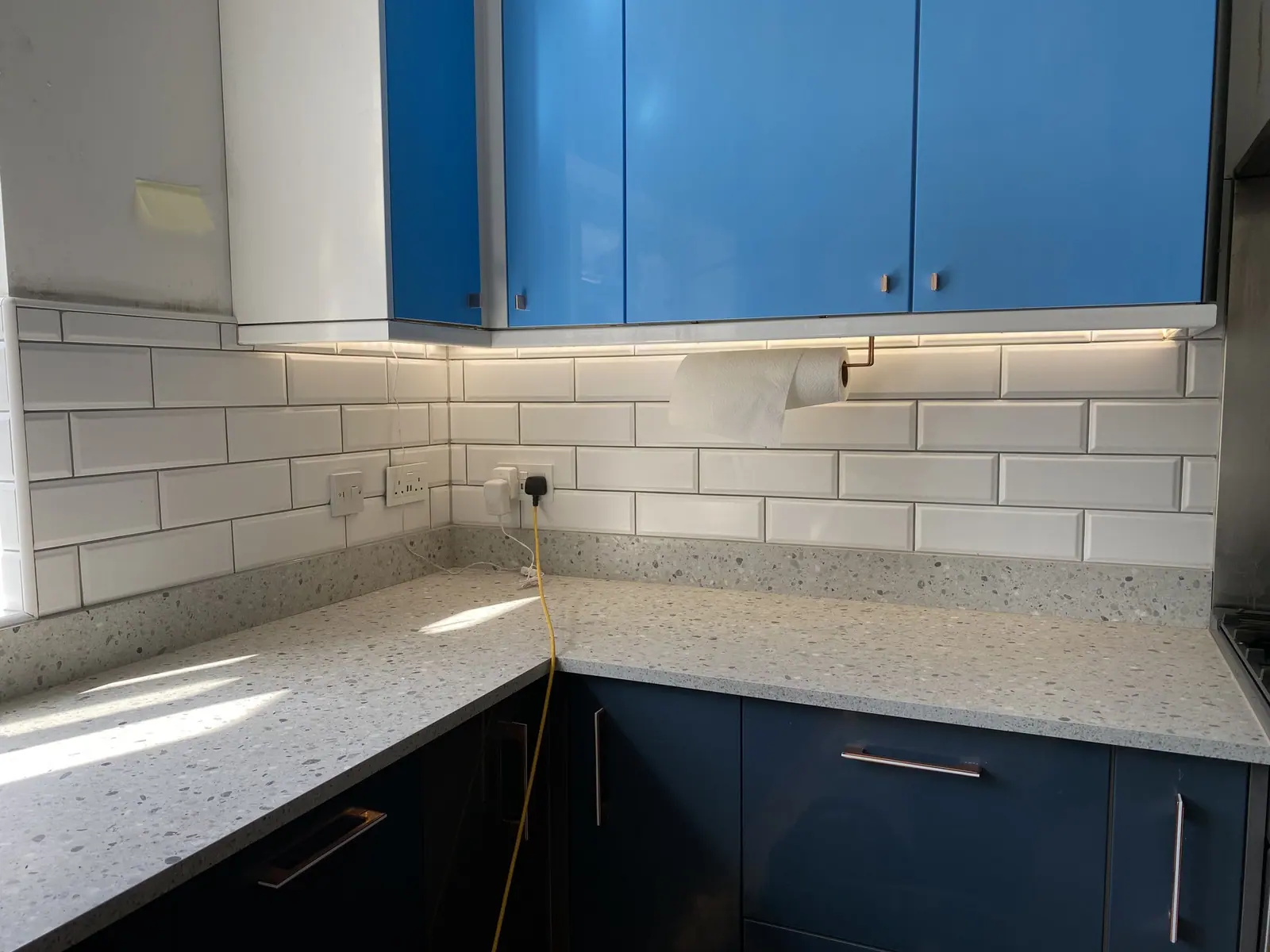 Navy kitchen units with white sparkle quartz worktop, white metro tile splashback and under-cabinet lighting, fitted by Basingstoke Bathrooms